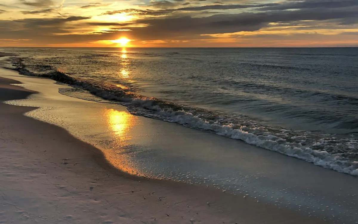 Low golden sun over the Gulf and wet sand on Okaloosa Island in Fort Walton Beach